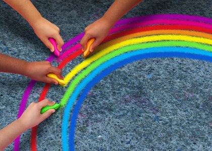 Barnehender tegner regnbue på asfalten med kritt - Klikk for stort bilde